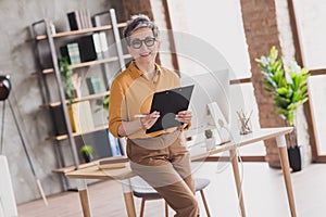 Photo of lovely mature lady look camera hold documents dressed yellow formalwear modern workplace success business owner