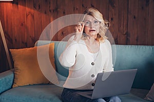 Photo of lovely retired woman sit sofa netbook nervous read news dressed casual outfit cozy home interior living room in