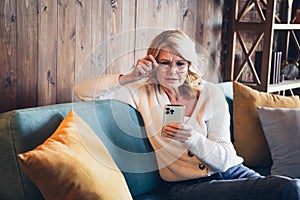 Photo of lovely retired woman sit sofa read worried news device dressed casual outfit cozy home interior living room in