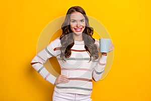 Photo of lovely satisfied girl toothy smile arm hold coffee cup isolated on yellow color background