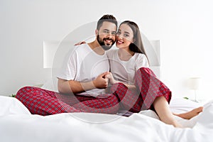 Photo of loving couple girl guy sit bed hold hands together cuddle in house indoors