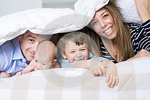 Photo of loving family four lying on white bed in morning.