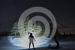 Photo with low lighting, silhouette of a man with a knife in his hand in a winter forest