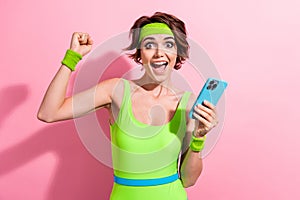 Photo of lucky excited lady dressed green sportive bodysuit winning game modern gadget isolated pink color background