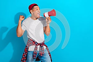 Photo of lucky excited man wear grey t-shirt shouting loud speaker empty space isolated blue color background