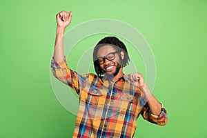 Photo of lucky funky dark skin man wear plaid shirt spectacles smiling rising fists dancing  green color