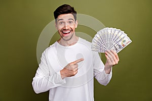 Photo of lucky guy pointing finger to his winnings in lottery las vegas casino player celebrate wealth isolated on khaki