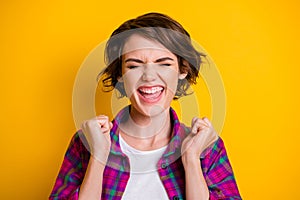 Photo of lucky overjoyed woman hold fists closed eyes anticipate wish isolated on yellow color background