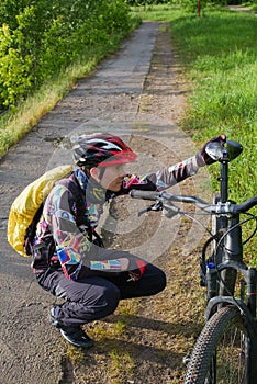 Photo of male cyclist wearing helmet next to bicycle on road in woods d