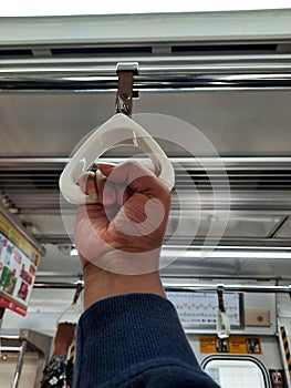 Photo of a male hand holding a handgrip inside an electric train in Jakarta, Indonesia