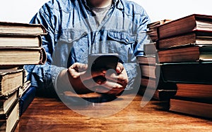 Photo of male person holding smartphone amidst old books