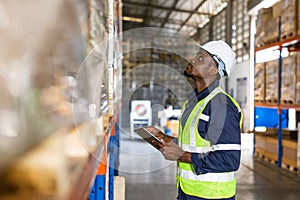 Photo of a male worker inspecting count products stock in a warehouse manufacturing plant for inventory management work