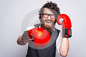 Photo of man with beard wearing suit and punching with boxing gloves