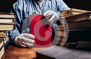 Photo of man in a blue shirt and white gloves holding a red book