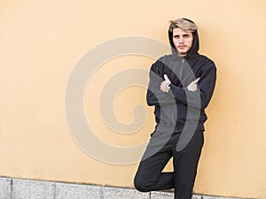 Photo of a man with a confident pose leaning against a wall