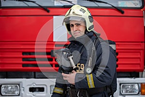 Photo of man fireman with mask in hands near fire truck