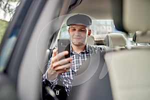 Photo of man with phone in his hands driving car.