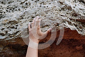 Photo of man`s hand clambering over rock