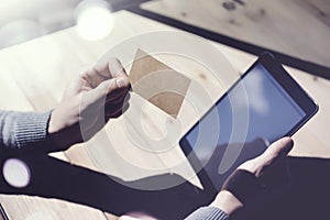 Photo Man Showing Blank Craft Business Card, Holding Hand Modern Digital Tablet.Wood table Blurred Background.Mockup