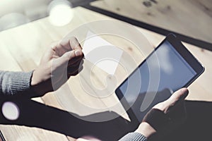 Photo Man Showing Blank White Business Card, Holding Hand Modern Digital Tablet.Wood table Blurred Background.Mockup