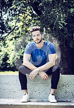 Photo of a man sitting on a cement bench in front of a tree