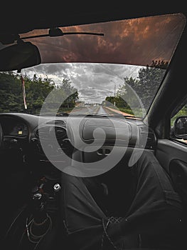 Photo of a man sitting on the seat of a car that is driving on the highway