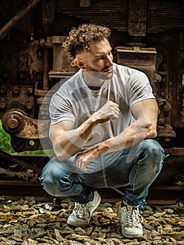 Photo of a man sitting on a train track next to a train