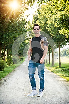 Photo of a man standing on a dirt road surrounded by trees