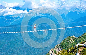 Photo of a man walking on a cable car over an abyss in the mountains