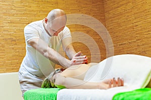 Photo of masseur performing traditional Thai massage on woman back in the spa salon. Beauty treatment concept