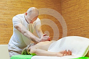 Photo of masseur performing traditional Thai massage on woman back in the spa salon. Beauty treatment concept