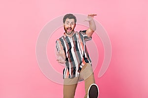 Photo of mature age positive man in striped shirt hands towards him dancing having fun discotheque isolated on pink