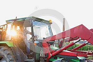 Mature farmer driving tractor in field with lens flare in background photo