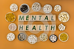 Photo on mental health theme. wooden cubes with the inscription `mental health`, and biologically active supplements