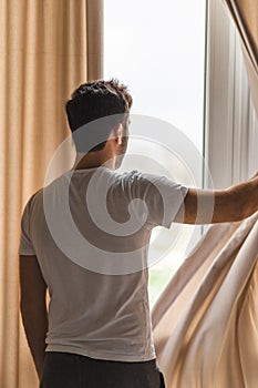 Photo of middle age bearded man looking in the window in the morning.