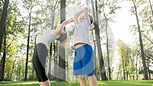 Photo of middle aged mother with her teenage boy child doing yoga and breathing exercises at park. Family taking care of