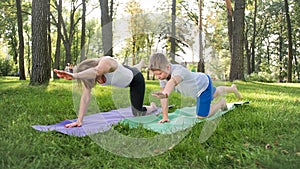 Photo of middle aged mother with her teenage boy child doing yoga and breathing exercises at park. Family taking care of