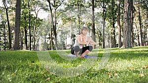 Photo of middle aged smiling woman practising yoga asana. Persong meditating in nature. Balance and harmony of body and