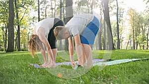 Photo of middle aged woman teaching her student in yoga class at park. Woamn with teenage boy practising fitness