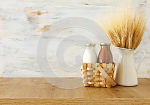 Photo of milk and chocolate next to wheat over wooden table and white background. Symbols of jewish holiday - Shavuot