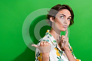 Photo of minded adorable girl wear trendy clothes arm touch face look up empty space offer banner isolated on green