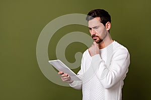 Photo of minded confident man wear white trendy clothes browsing web site empty space  on khaki color background