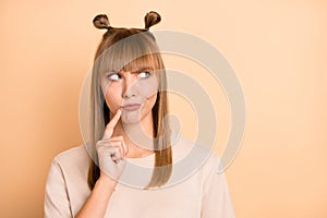 Photo of minded distrustful girl finger chin look empty space wear t-shirt isolated beige color background