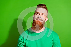 Photo of minded dreamy man with long ginger beard dressed green t-shirt look at sale empty space isolated on green color
