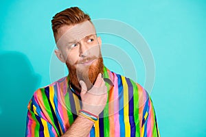 Photo of minded groomed man wear striped clothes arm touch beard look up empty space isolated on cyan color background