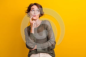 Photo of minded lovely girl dressed trendy clothes watching empty space banner isolated on yellow color background