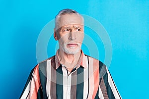 Photo of minded serious man wear striped trendy clothes look empty space isolated on blue color background