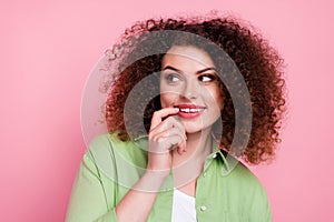 Photo of minded woman with perming coiffure dressed stylish shirt look empty space finger on lips isolated on pink color