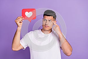 Photo of minded young thoughtful man look hold hand heart icon finger head isolated on violet color background