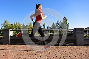 Photo of modern young woman in sports clothing jumping while exercising outdoors